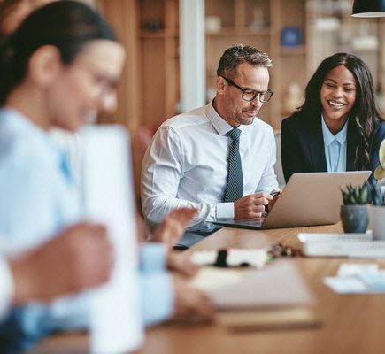 businesspeople smiling while working on a laptop together